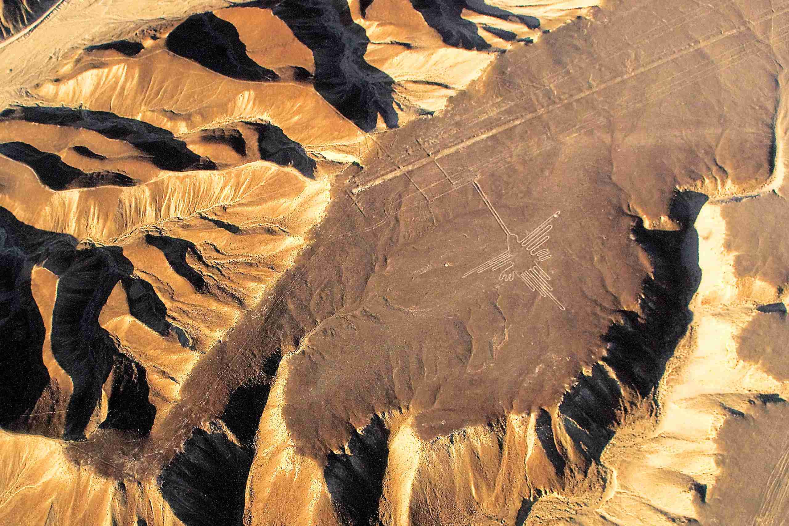 O geoglifo do Beija-flor Geoglifo do Beija-flor em um platô escuro do deserto cercado por morros erodidos, Linhas de Nazca, Peru