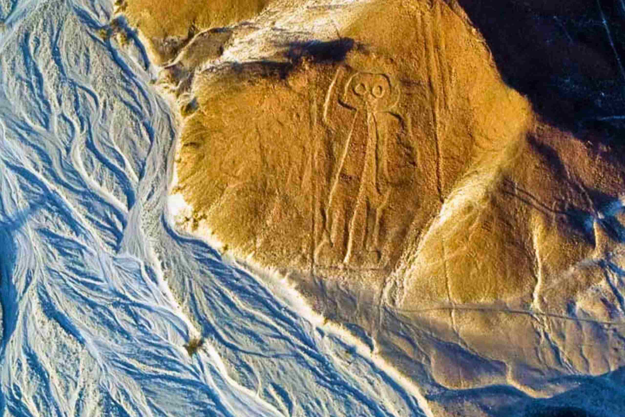 El geoglifo del Astronauta en una ladera del desierto de Nazca junto a un cauce seco, visto desde el aire