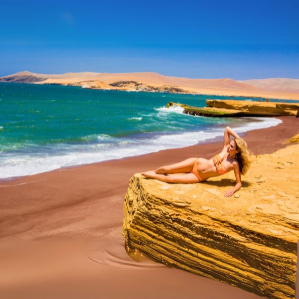Traveler sunbathing on a sandstone ledge above the red sands and turquoise water of Playa Roja in the Paracas National Reserve