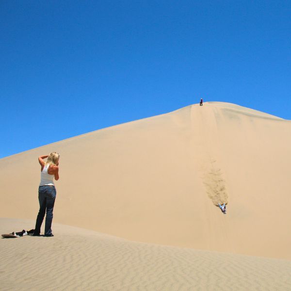 Sandboarding down a massive desert dune